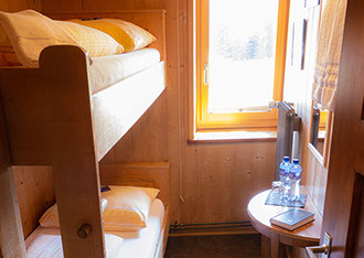 Bildbeschreibung: kleines Hotelzimmer mit zwei Betten übereinander im Berghotel Sartons, Valbella.